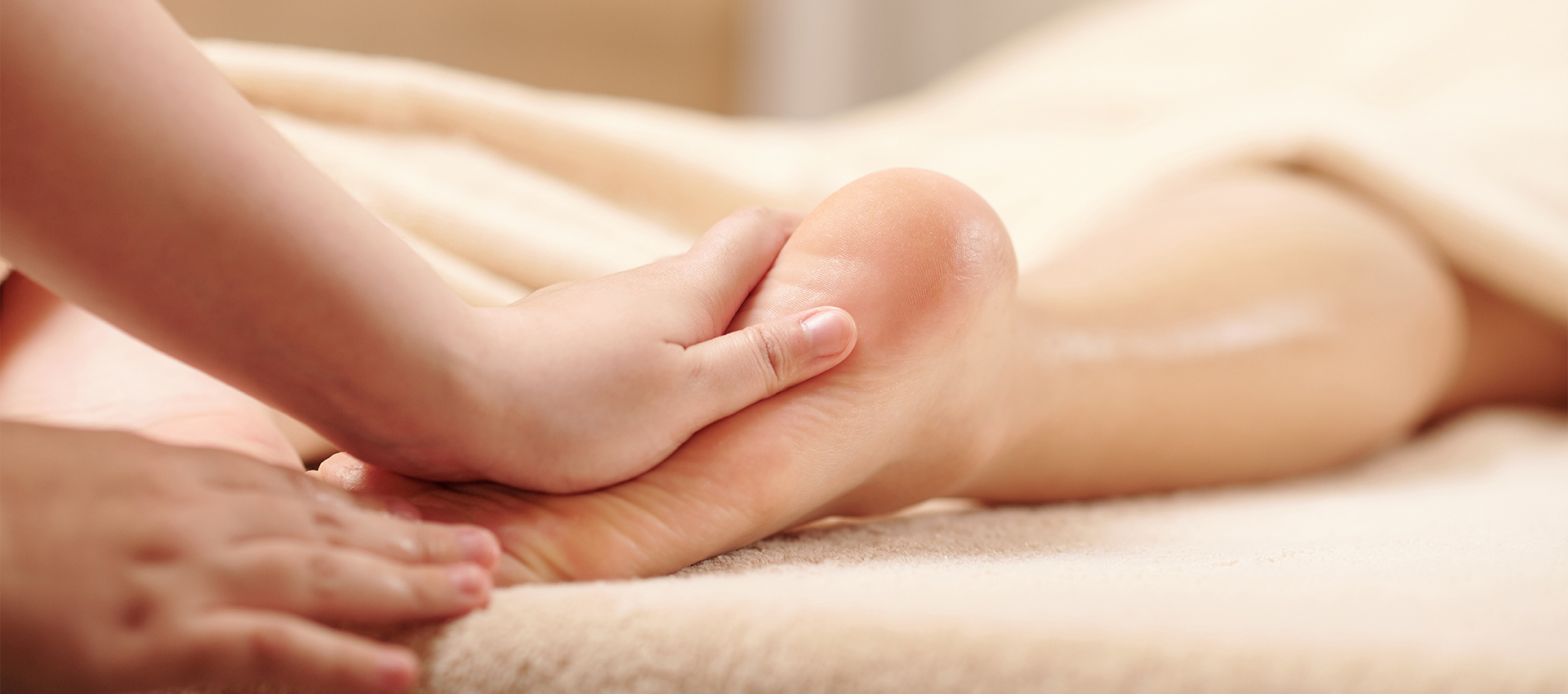 Hands of therapist massaging feet of young woman with moisturizing oils