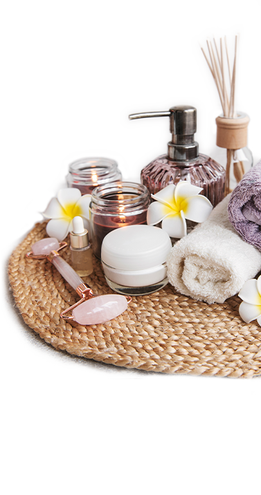 Spa set, essential oil, massage salt, candle and frangipani flowers on gray concrete background